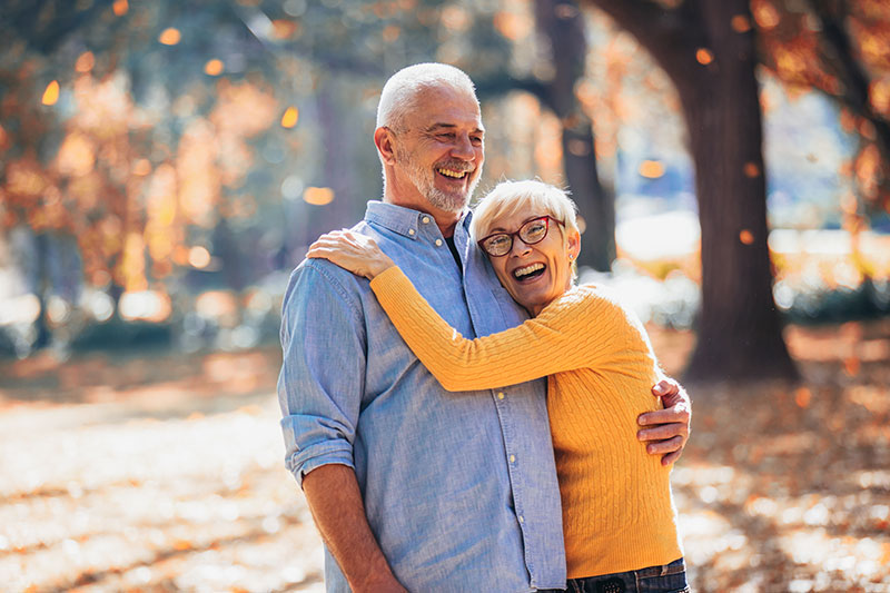older couple smiling under the falling leaves